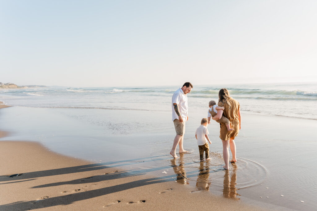 Family walking toward the ocean at sunset during a Lincoln City Oregon beach photo session.